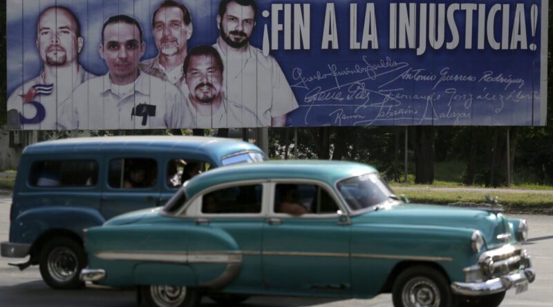 Cars drive past a banner of five Cuban prisoners held in U.S. custody, two of whom were previously released, in Havana
